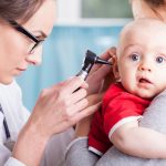 Doctor examining baby boy with otoscope